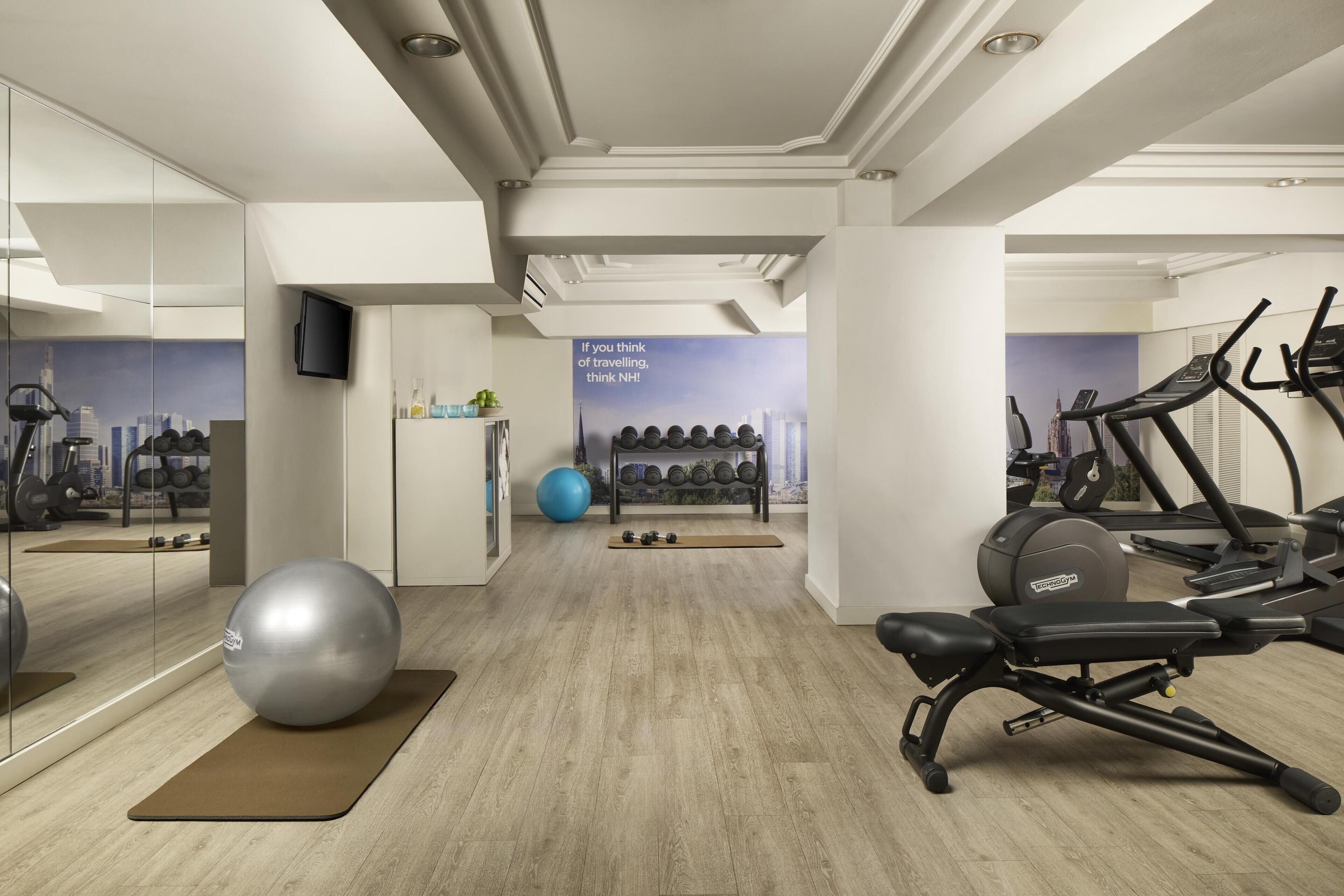 A modern gym with exercise equipment, a large mirror, and a motivational poster.