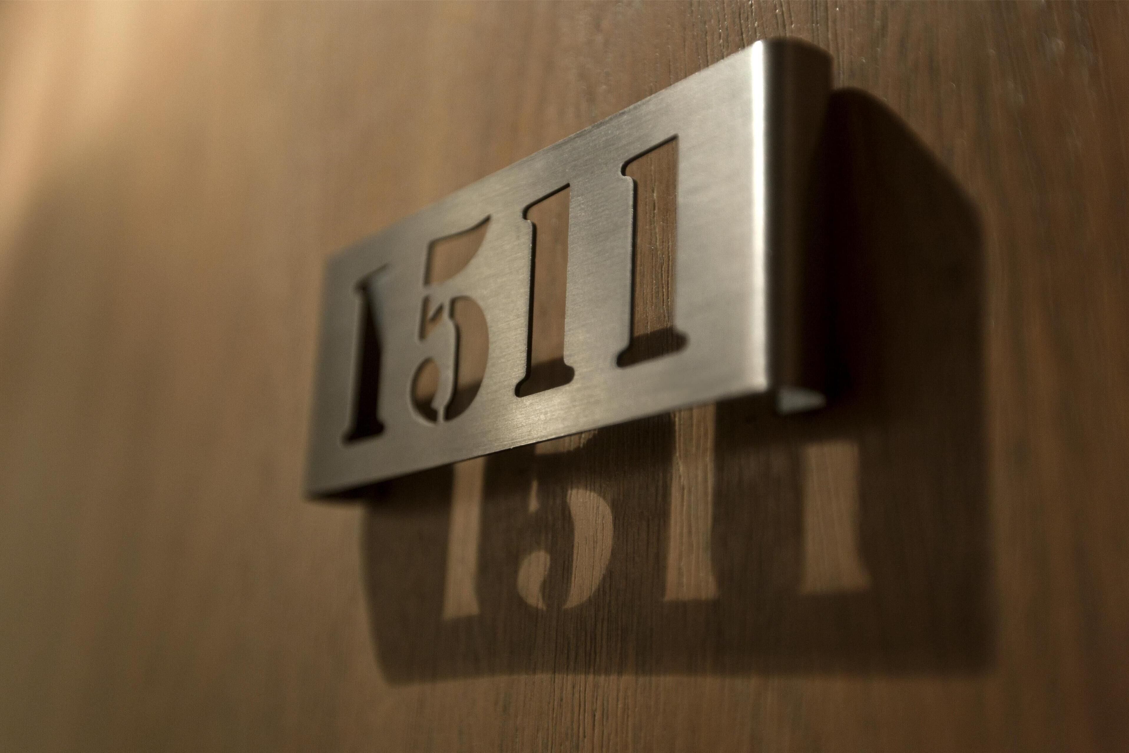 Une plaque métallique portant le numéro 1511, fixée sur une surface en bois.