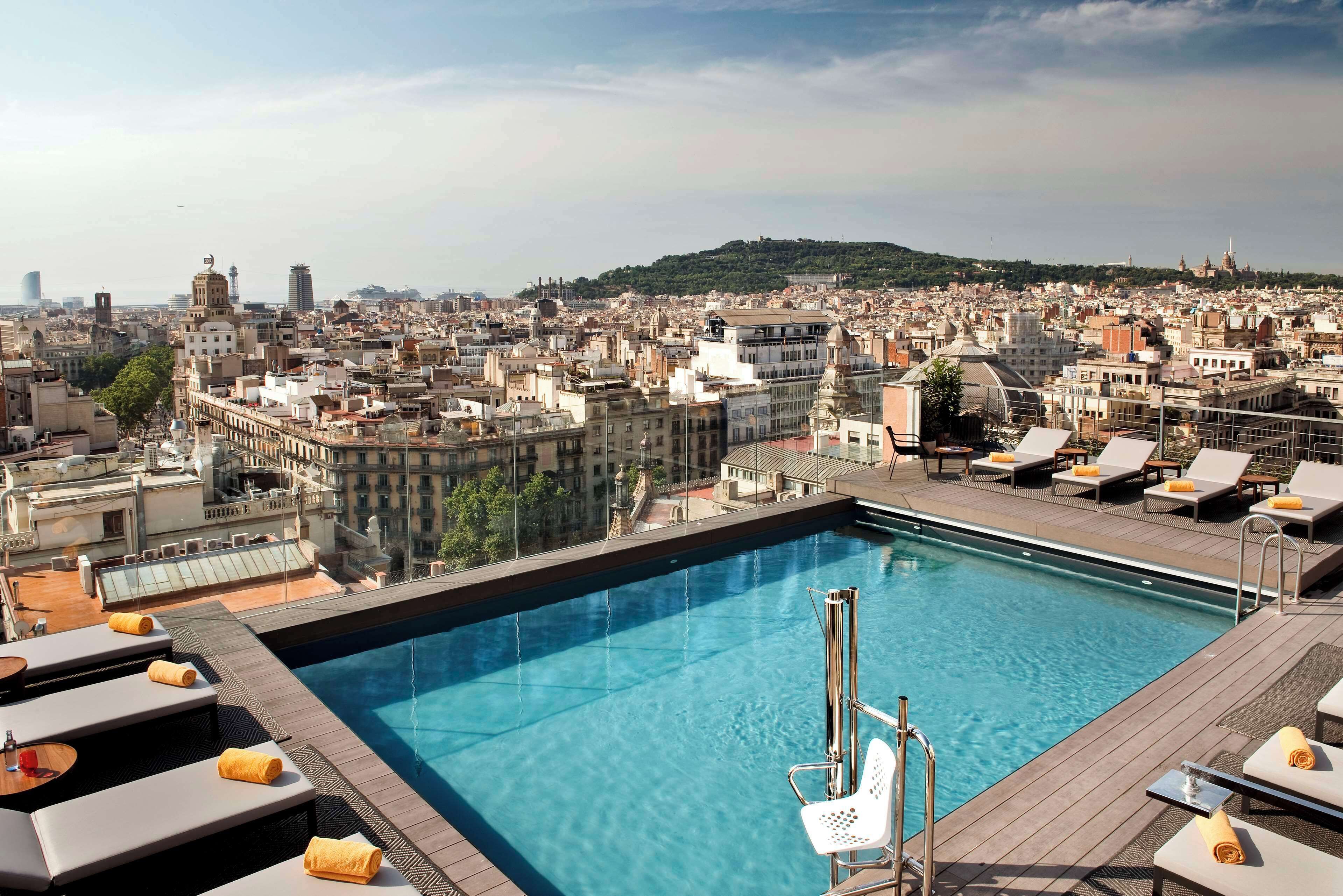 A rooftop pool with lounge chairs and a city view.