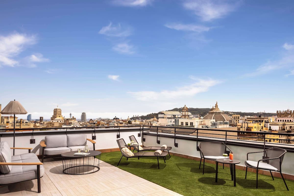 A rooftop terrace with outdoor seating, a view of the cityscape, and a decorative lamp.