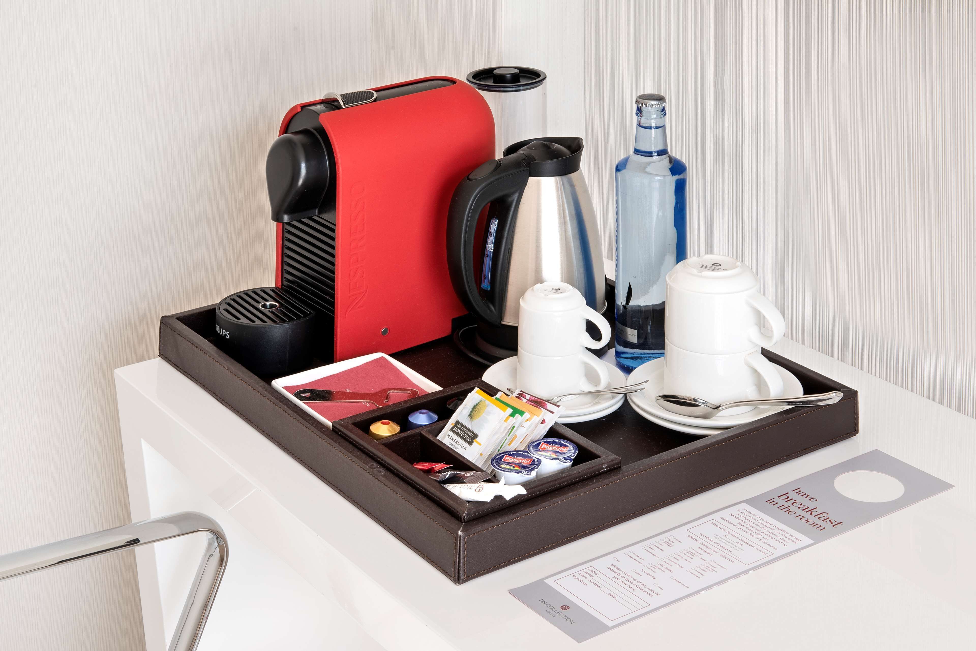 A breakfast trolley with a coffee maker, kettle, water bottle, and tea set.