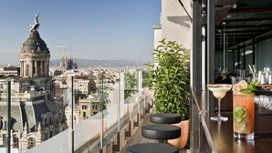 Um bar no terraço com vista para a cidade, um balcão de bar e um vaso de planta.