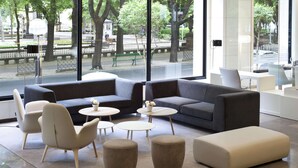 Un interior moderno con un ventanal grande, un sofá gris, dos sillones y una mesa de centro.