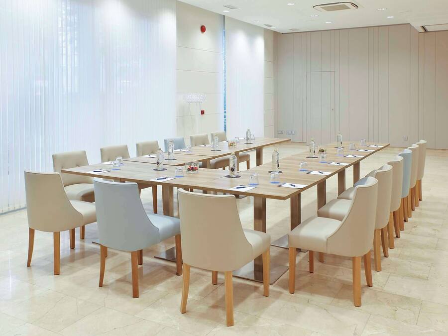 Un salón de conferencias con una larga mesa, varias sillas y un diseño moderno.