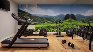 A gym with treadmills, a stationary bike, and a wall mural of a green landscape. - NH Ciudad de Cuenca (Cuenca)