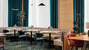 A modern dining area with round tables, cushioned seating, and pendant lighting. - NH Ciudad de Cuenca (Cuenca)