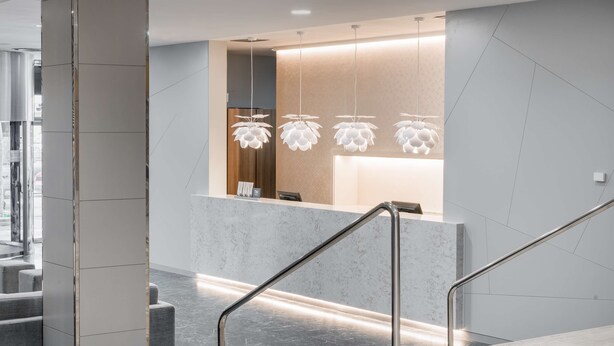 A modern reception area with a marble counter, metal railings, and unique hanging lights. - NH Ciudad Real (Ciudad Real)