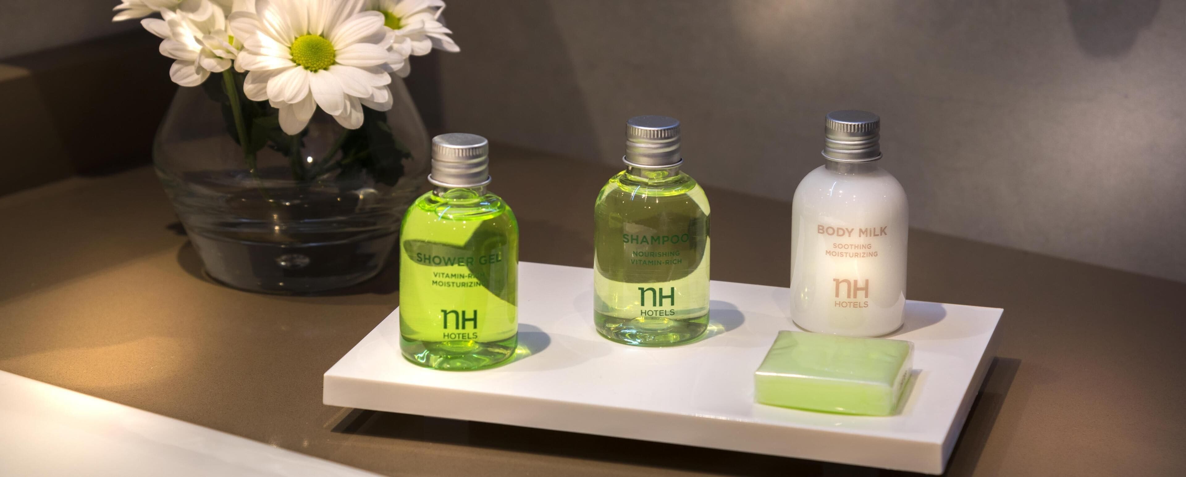 Tres botellas de artículos de baño de hotel sobre una bandeja blanca.
