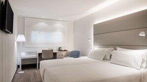 A hotel room with two beds, a desk, a chair, a flat-screen TV, and a projector screen. - NH Ciudad Real (Ciudad Real)