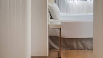 Un dormitorio con cama, mesita de noche y ventana con cortinas.