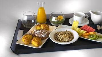Un plateau contenant divers éléments pour le petit-déjeuner, notamment des croissants, des céréales, des fruits et des boissons.