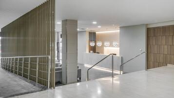A modern hotel lobby with a marble floor, a reception desk, and a wooden partition wall.