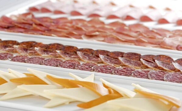 A variety of cured meats and cheeses displayed in a white tray. - NH Ciudad Real (Ciudad Real)