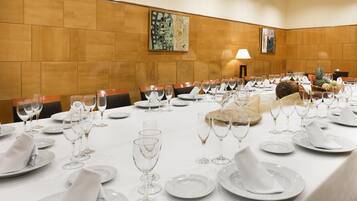 A conference room with a long table set for a meeting, equipped with chairs, plates, and wine glasses.