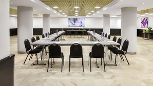 A conference room with a long table, chairs, and a large screen at the front. - NH Ciudad de Santander (Santander)