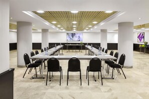 A conference room with a long table, chairs, and a large screen at the front. - NH Ciudad de Santander (Santander)