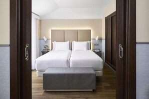 A double bed with a headboard, bedside tables, and a bench in a hotel room.