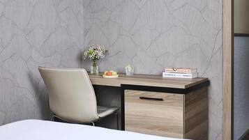 A modern desk with a vase of flowers, a glass of water, and a box of macarons.