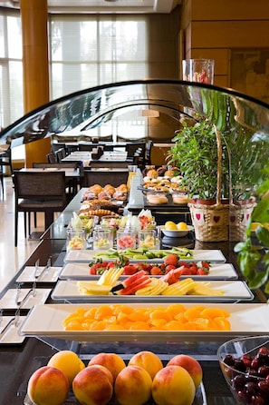 A buffet with various fruits, pastries, and beverages.