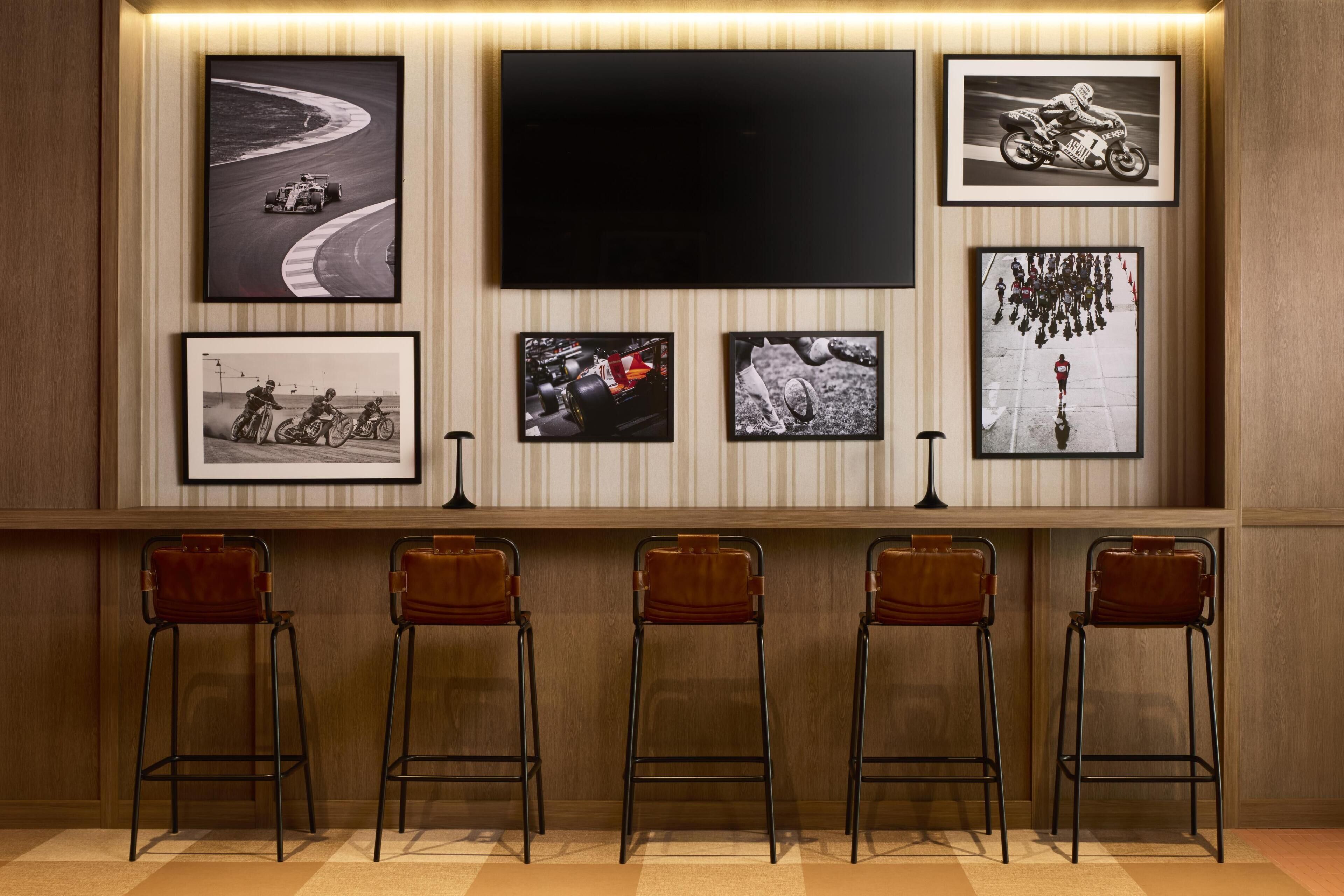 A bar area with a flat-screen TV, framed photos, and four bar stools.
