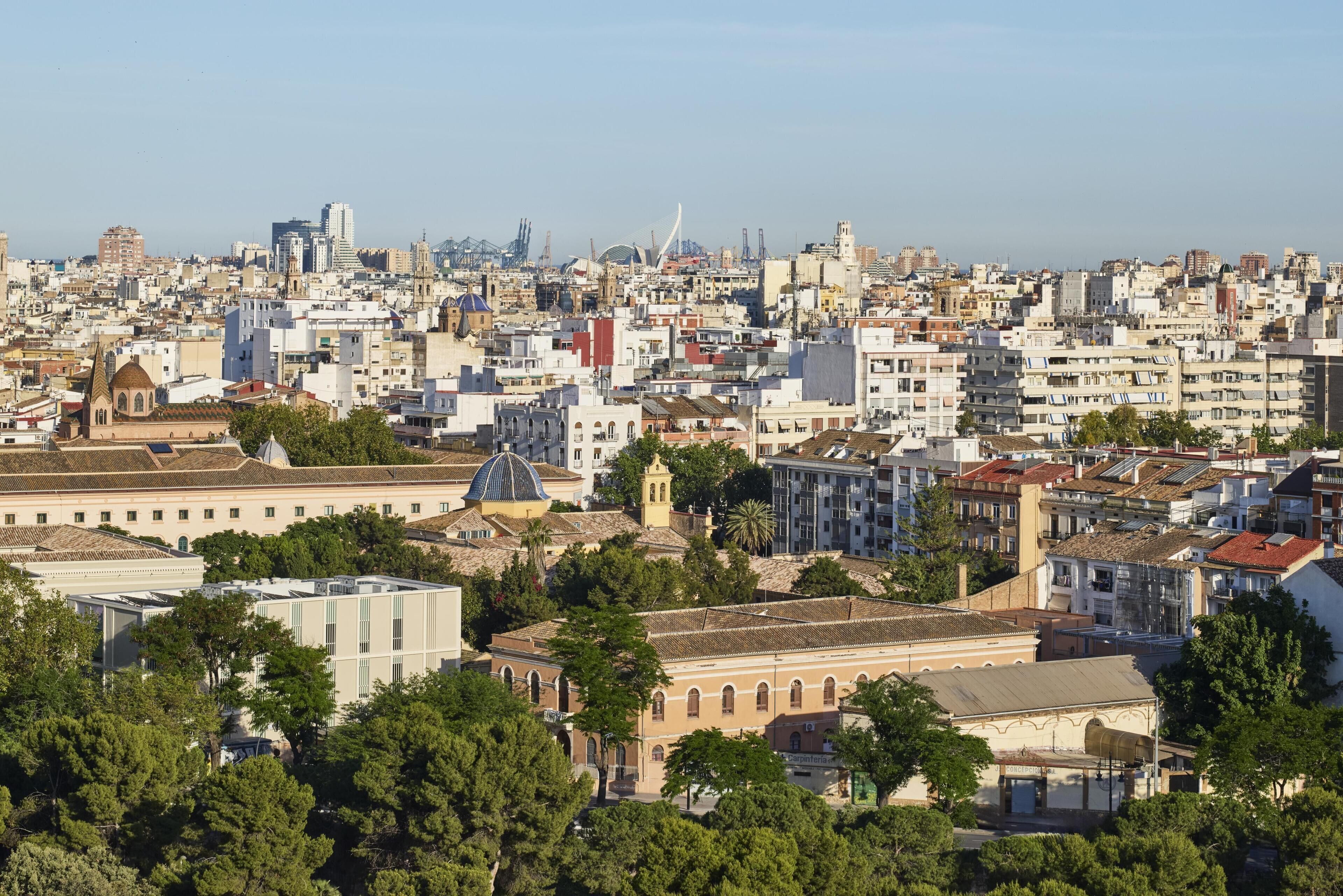 A densely packed urban area with historical architecture, including a prominent church with a dome and a bell tower, surrounded by modern buildings and greenery.