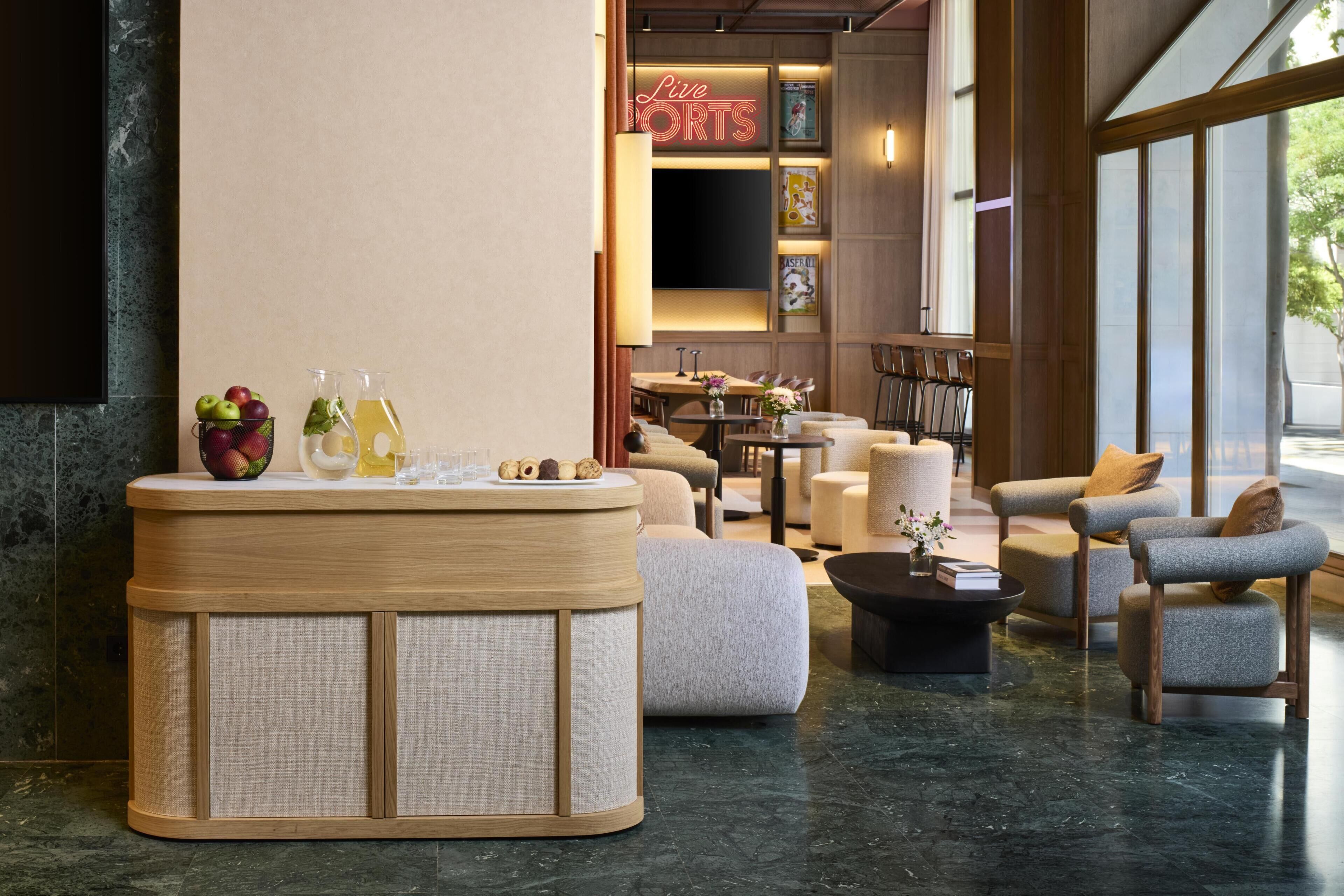 A modern lobby with a reception desk, seating area, and a large window.