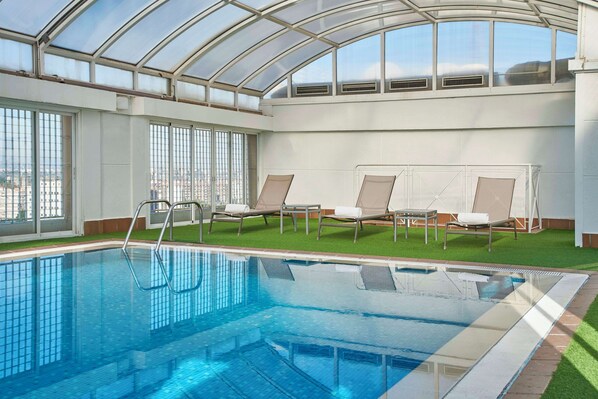 Una piscina al aire libre, sillones reclinables de piscina