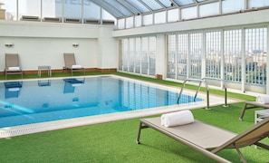 Una piscina al aire libre, sillones reclinables de piscina