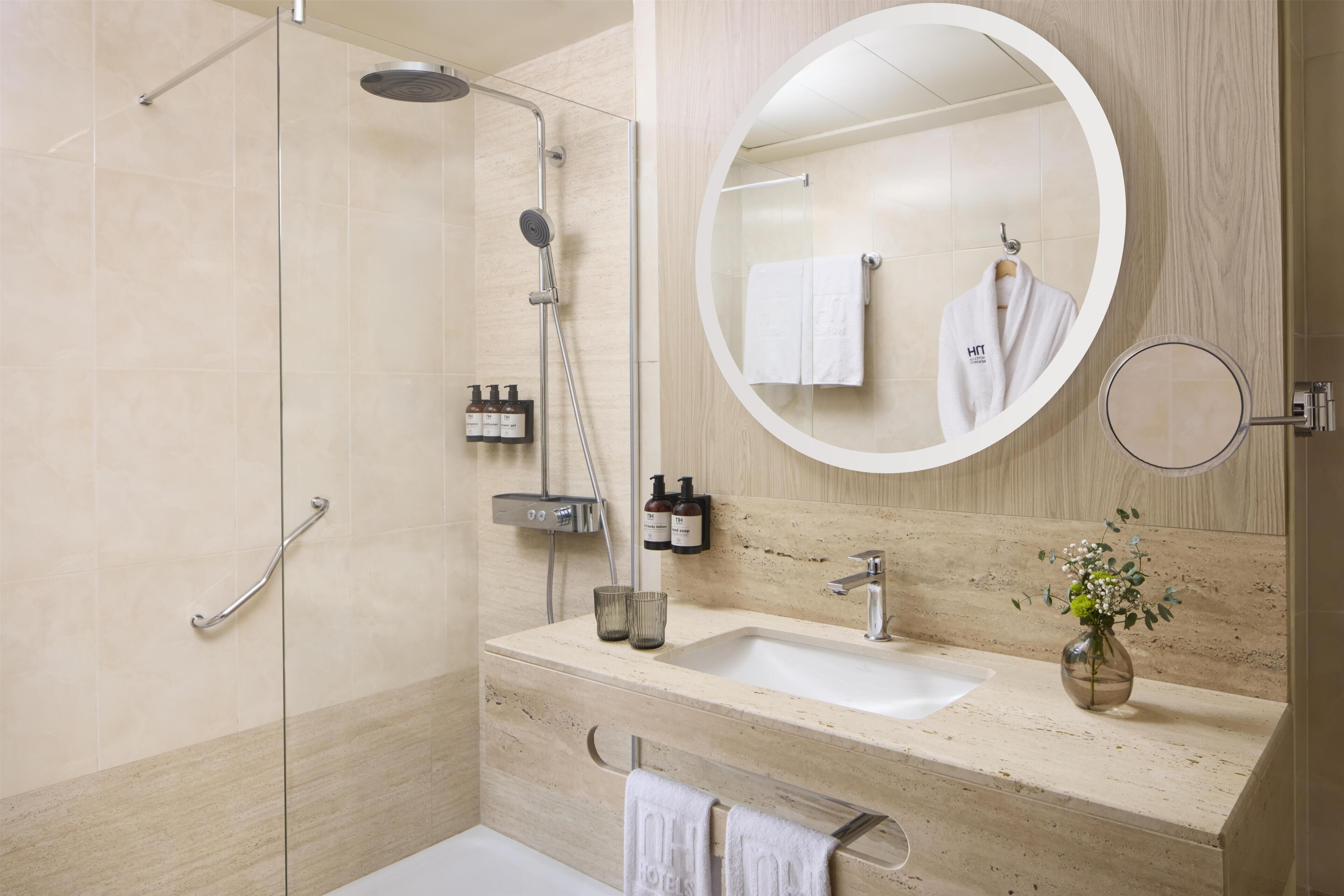 A modern bathroom with a glass shower enclosure, a sink with a mirror, and a towel rack.