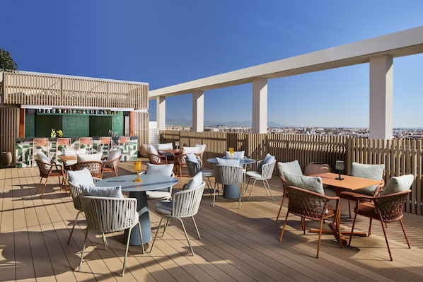 A rooftop terrace with outdoor seating, a bar area, and a view of the cityscape. - NH Valencia Center (Valencia)
