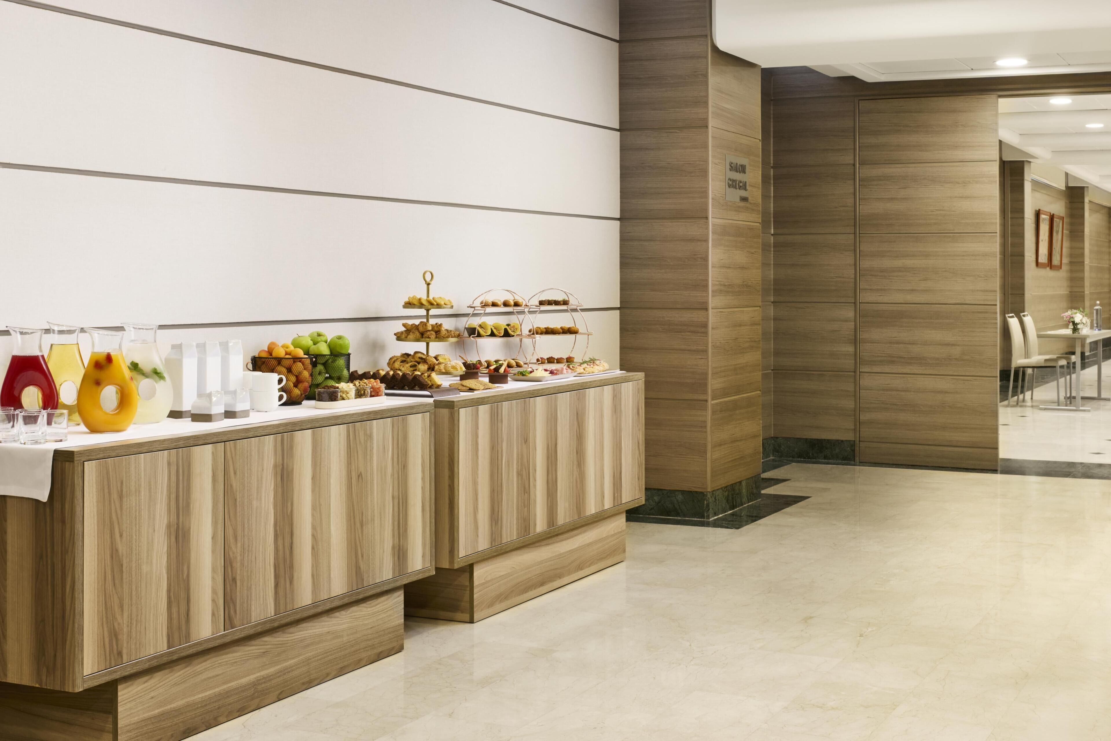 Zona de recepción con mostrador de buffet, panel de madera y suelo de mármol.