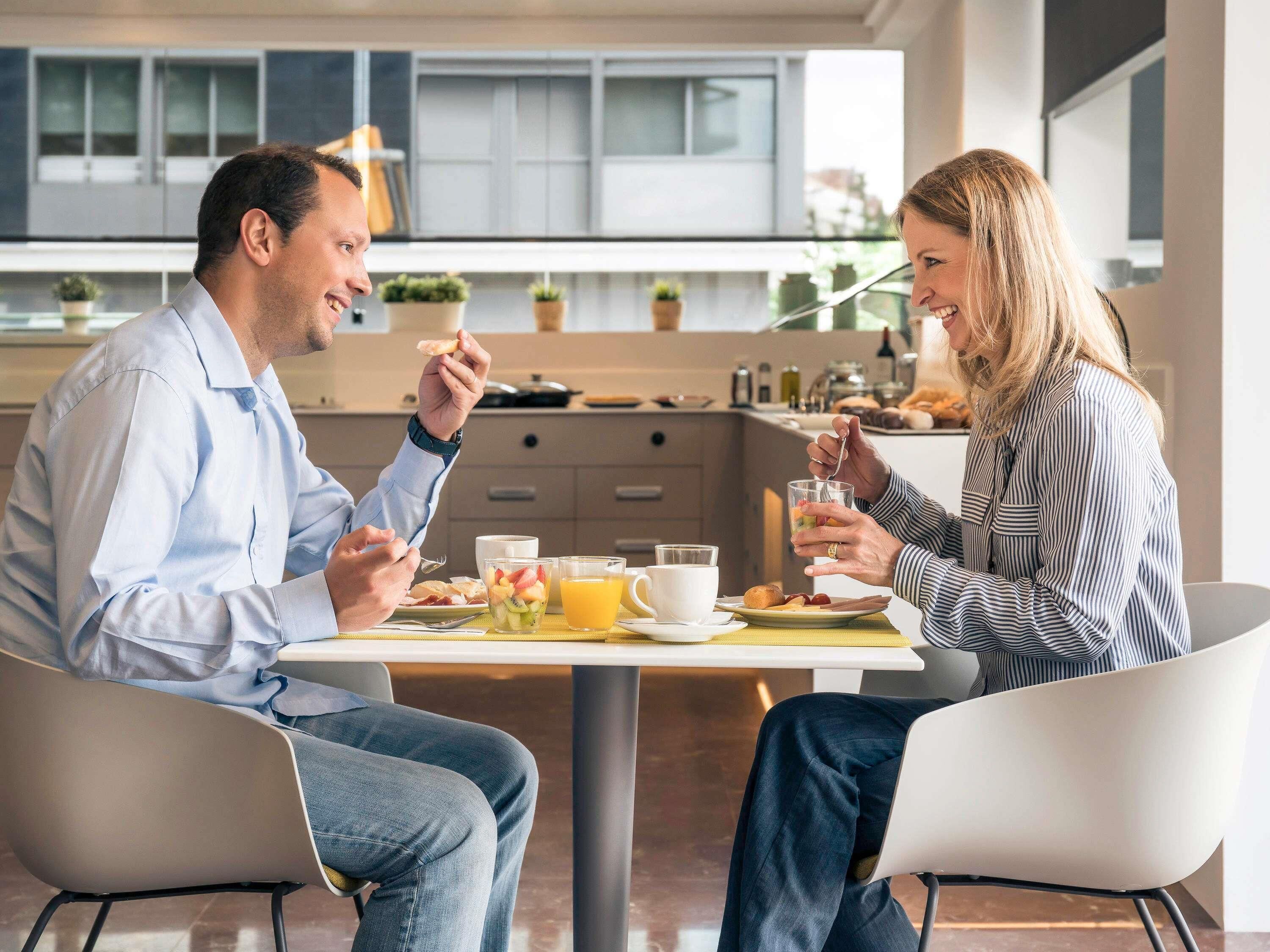 Une cuisine moderne avec une table à manger, des chaises et un coin repas pour le petit-déjeuner.