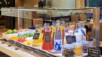 Un bufé de desayuno con diversas opciones de fruta y bebidas.