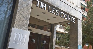 La façade de l’hôtel NH Les Corts, avec une enseigne bien visible et une entrée en verre.