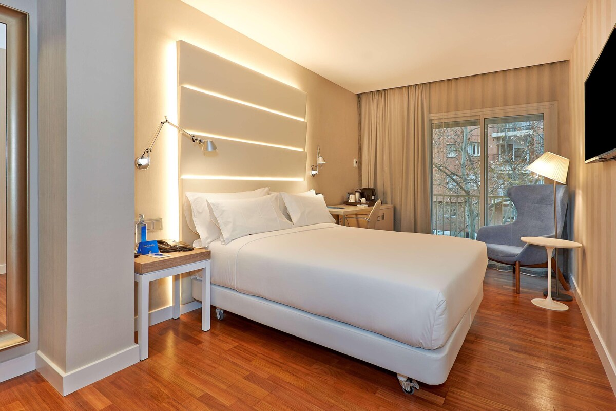 Une chambre d’hôtel moderne équipée d’un grand lit, de tables de chevet, d’un bureau, d’une chaise et d’un téléviseur.