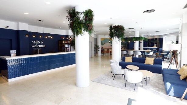 A modern reception area with a blue counter, white chairs, and a blue sofa.