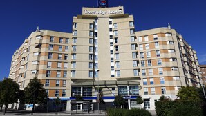 A Travelodge Hotel building with multiple floors, a central entrance, and a clear sky.