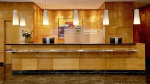 A reception desk with a marble floor, wooden paneling, and pendant lights. - NH Ciutat de Reus (Reus)