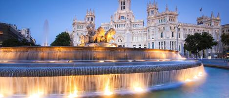 A grand historic building with a large fountain in the foreground.