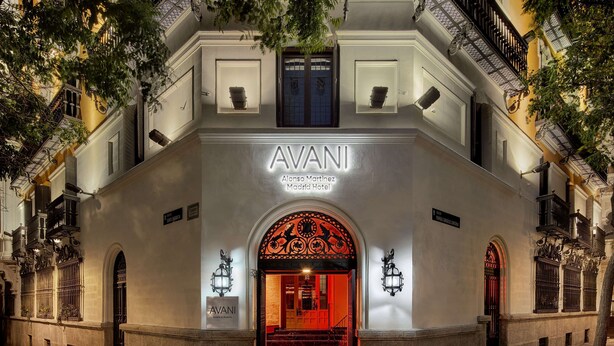 El exterior del Hotel AVANI Alonso Martinez Madrid, con una entrada imponente y un arco iluminado en rojo, además de un letrero sobre la puerta.