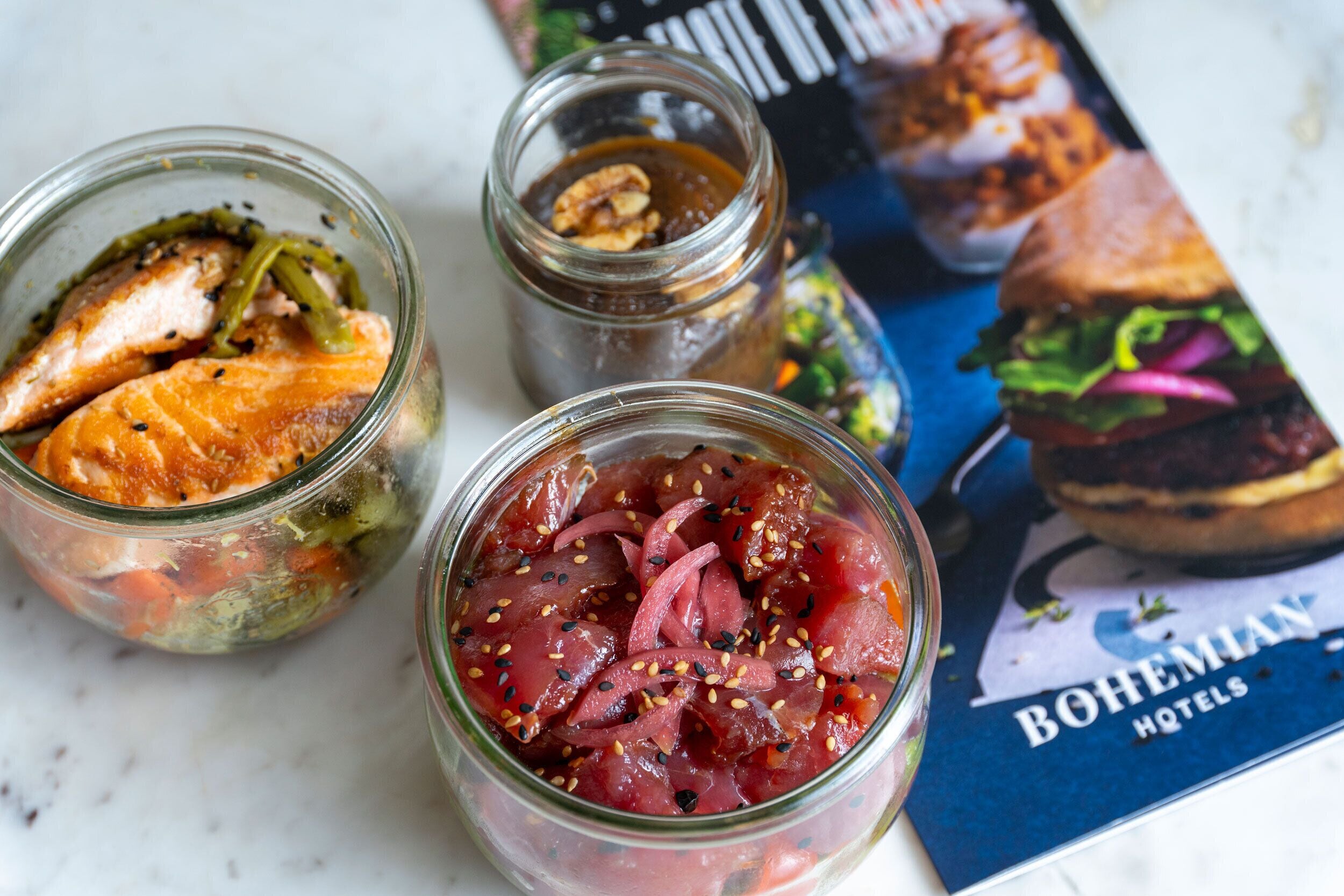 Two glass jars with food items, a menu, and a book.