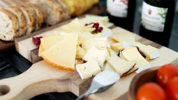 Una tabla de madera con queso, pan y una botella de vino.