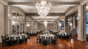 A large banquet hall with multiple round tables set for dining, a grand chandelier, and tall windows along the walls. - NH Collection Gran Hotel de Zaragoza (Zaragoza)