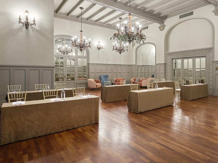 Una habitación amplia con piso de madera, una mesa larga con sillas y varias zonas de estar.