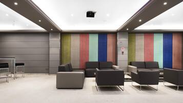 Un espace de détente moderne avec un sol gris, des canapés noirs et un mur rayé aux couleurs vives.