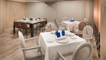 A dining area with tables set for four, each with white tablecloths, chairs, and blue glassware.