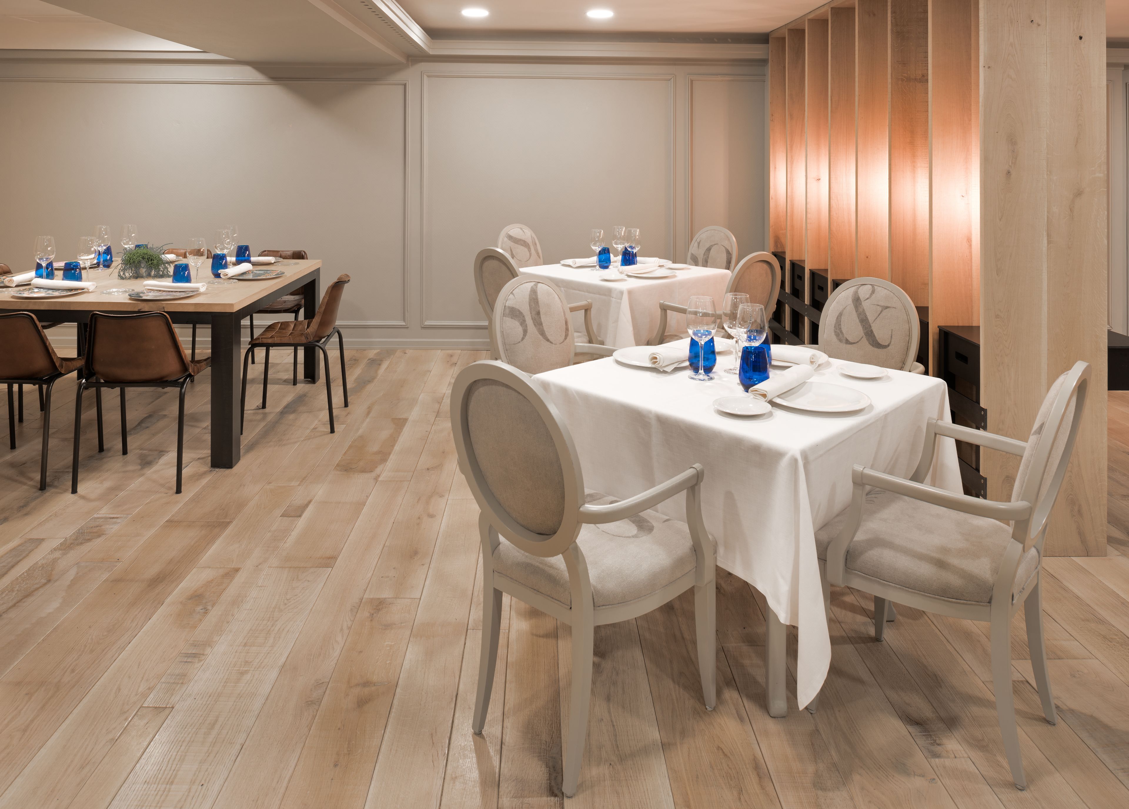 A dining area with round tables, chairs, and blue glassware.
