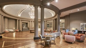 A spacious, elegantly designed lobby with a high ceiling, large columns, and a central chandelier. - NH Collection Gran Hotel de Zaragoza (Zaragoza)