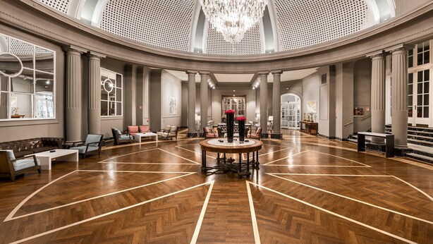A spacious lobby with a high ceiling, large windows, and a central round table. - NH Collection Gran Hotel de Zaragoza (Zaragoza)