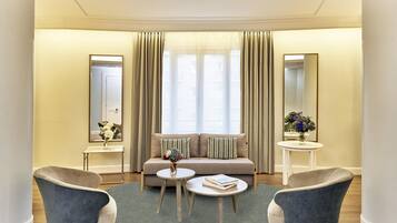 En moderne stue med sofa, to lænestole, et sofabord og et lille sofabord med en vase blomster.